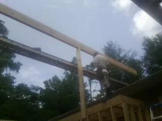 Carpenter setting a ridge beam over a new addition frame — Ice Dam Removal by Roofing Brothers in Rosamond