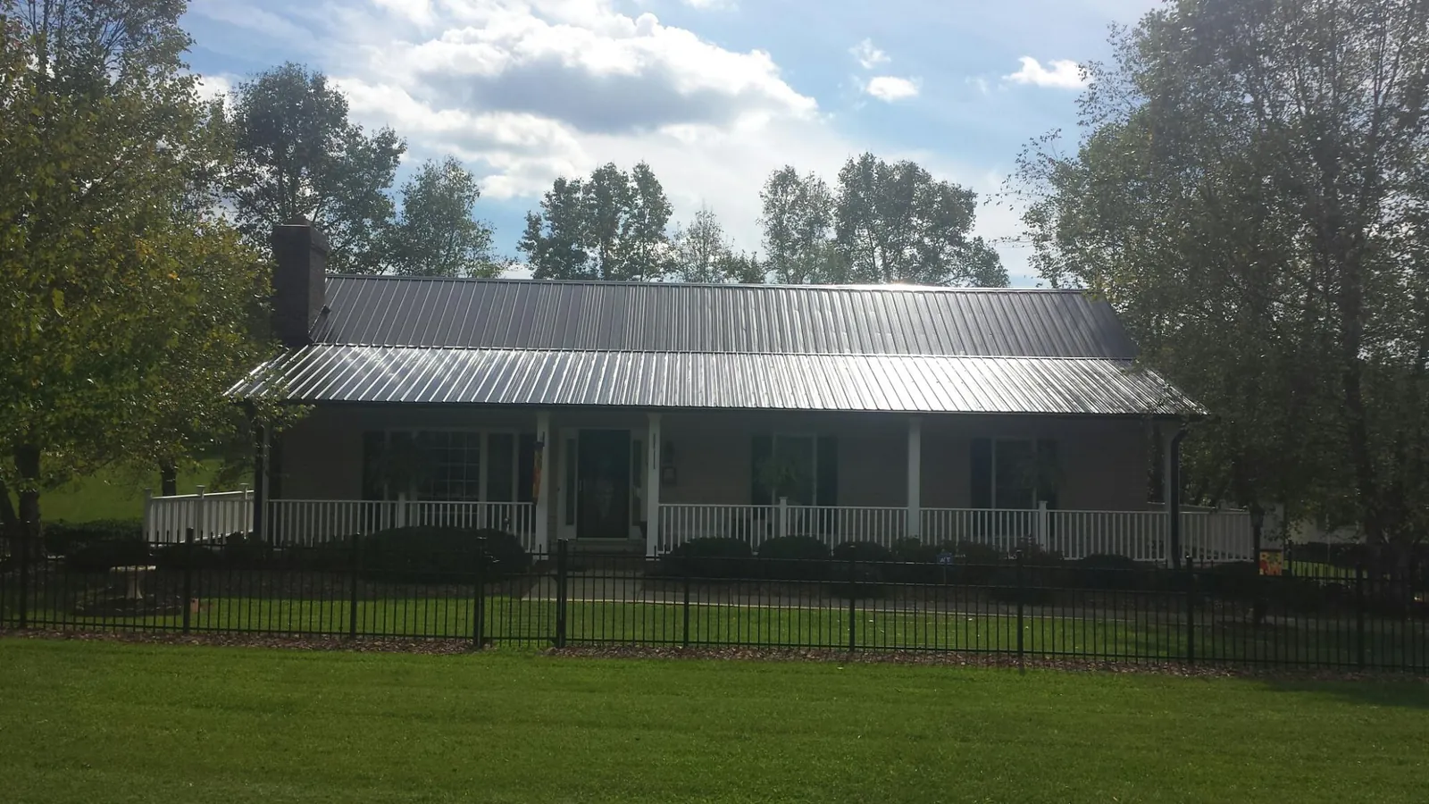 Gray metal roof on a brick ranch with a full width front porch — Gutter Guard Installation work by our crew in Rosamond
