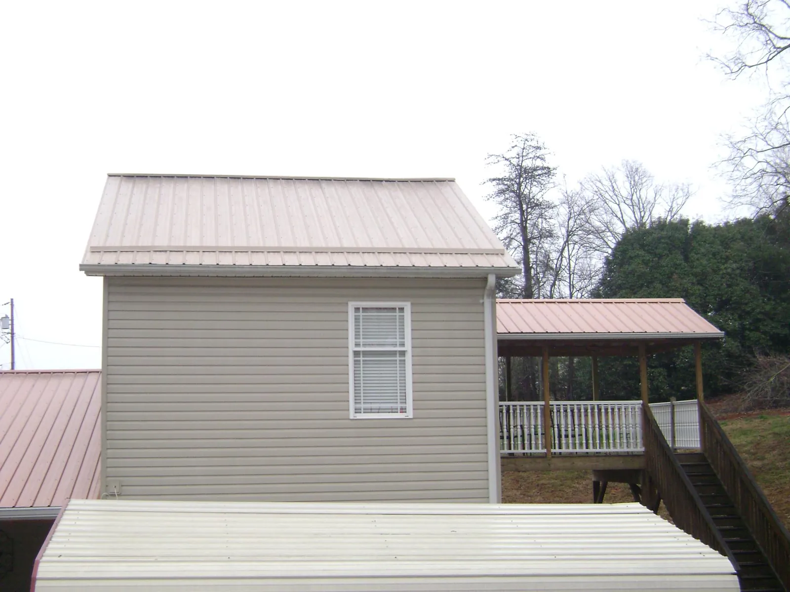 Tan metal roofs on a two story addition and attached porch, from a Roof Replacement job in Rosamond
