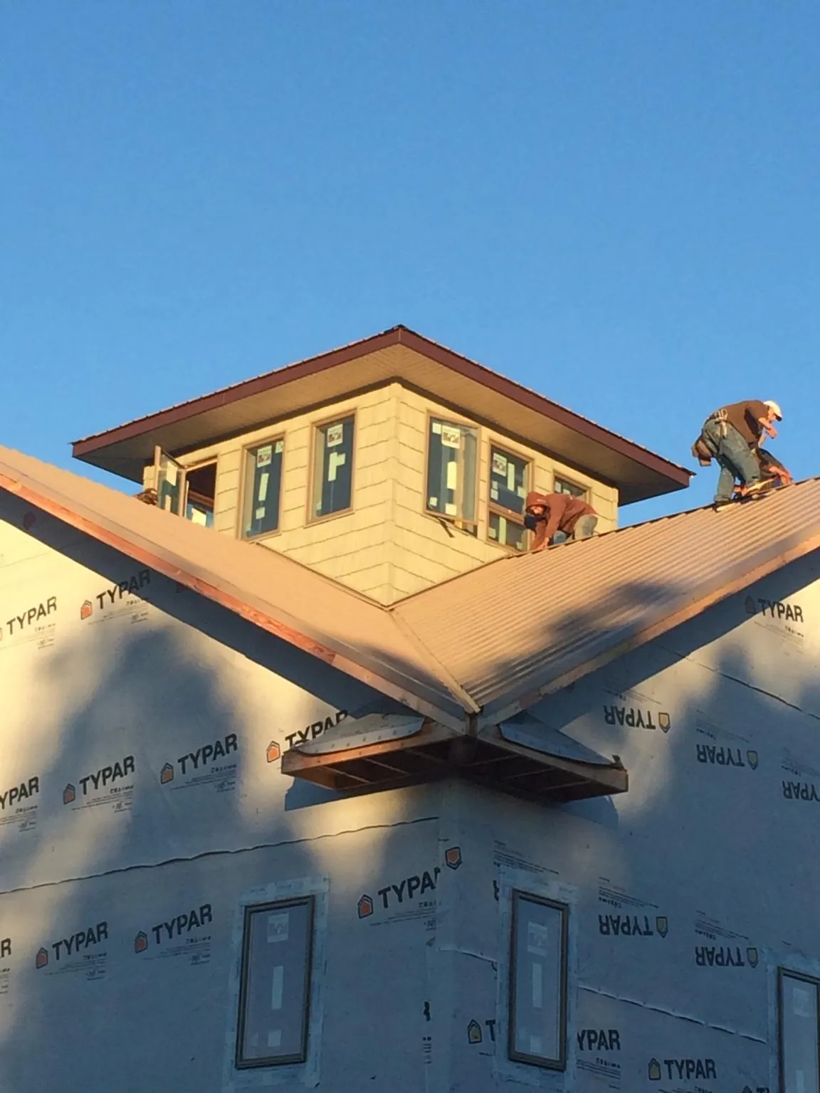 Roofers working around a rooftop cupola on a new metal roof at sunset — Roof Waterproofing in Rosamond by Roofing Brothers